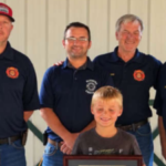 An 8-year-old Indiana boy spotted a smoking camper trailer and alerted people nearby before it caught fire; he was honoured with Department Patch and Certificate of Recognition for preventing a larger emergency