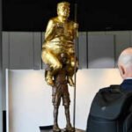 ‘The Orange Plague’: Why a golden, naked Trump is sitting on another man