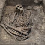 He was buried beneath a hearth, with a large stone pressed against his mouth and face, just one cm below the floor people walked on; researchers now suggest the 3,700-year-old burial was part of a magical ritual, not a punishment