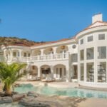 In 1991, John Stamos bought six acres in California for $430,000 and built a mansion; after later owners spent over $3 million renovating it, its asking price fell from $13 million to $6.4 million by 2026